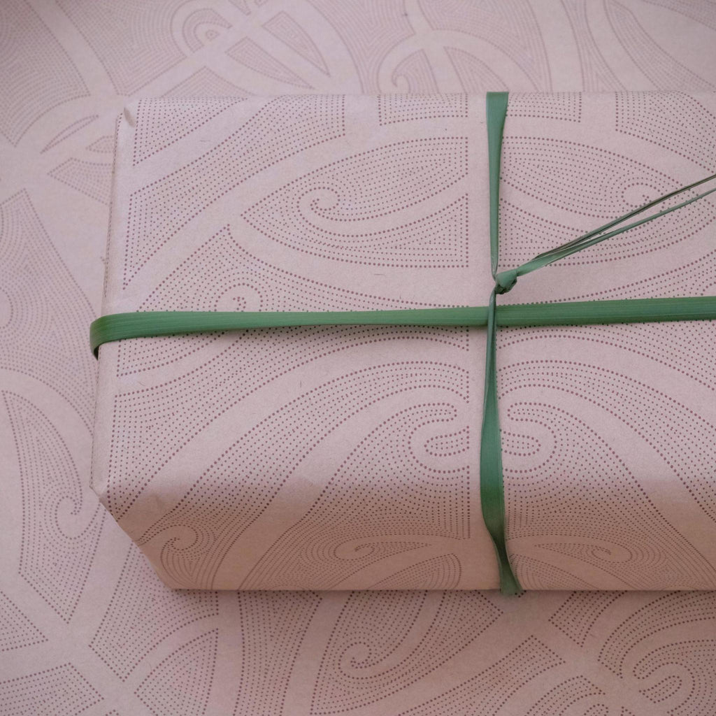 Māori wrapping paper with flax ribbon with māori design patterns in the background