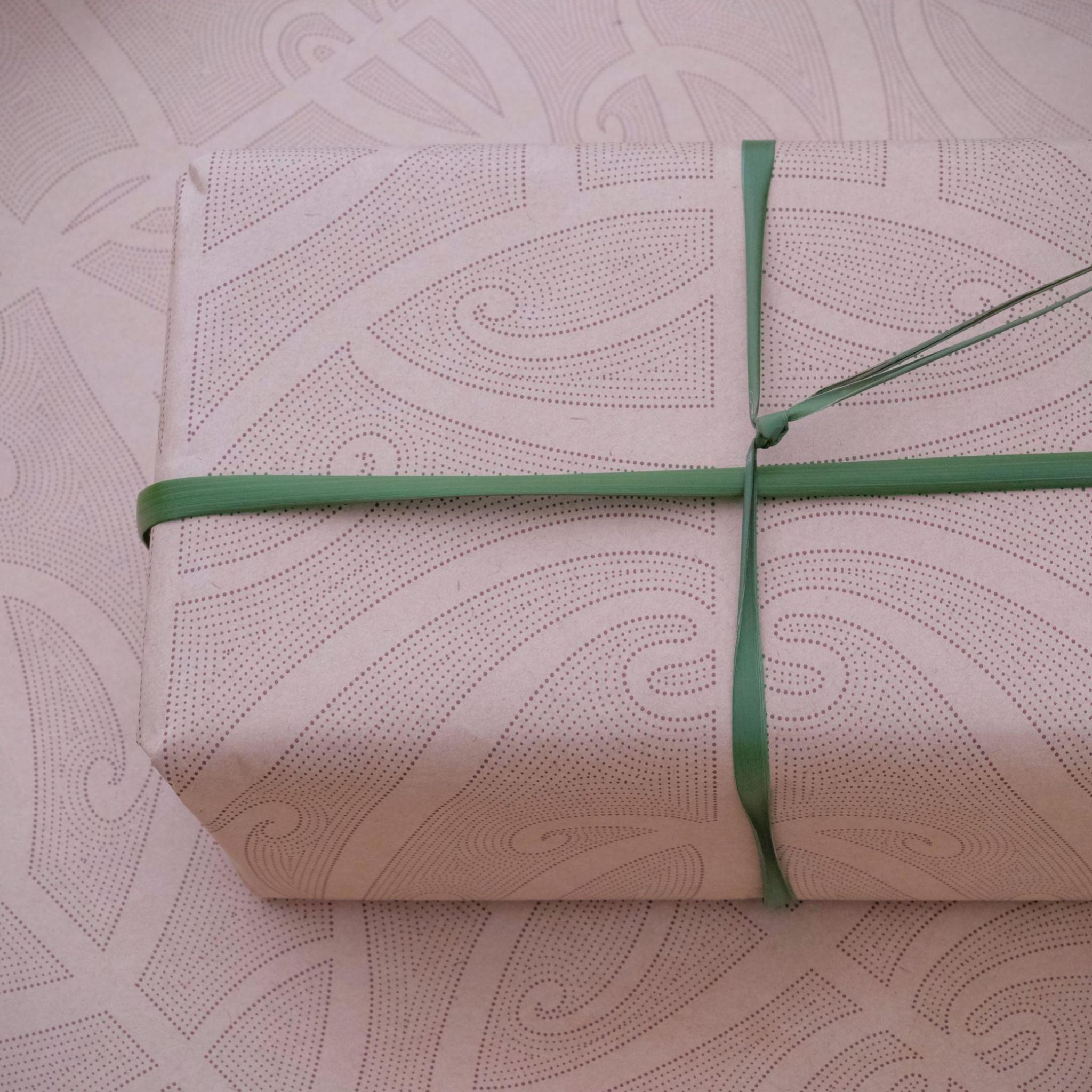 Māori wrapping paper with flax ribbon with māori design patterns in the background